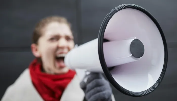 a woman in a red scarf shots in a loudhailer or megaphone