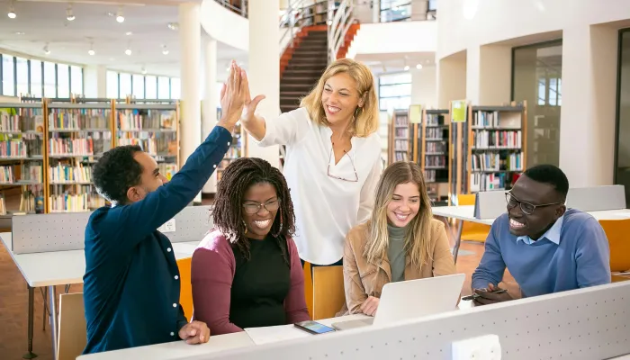 a group of young people in a library high five and collaborate