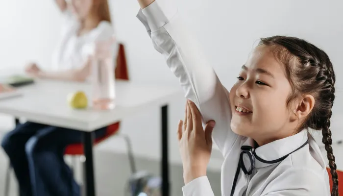 a schoolgirl raises her hand in class