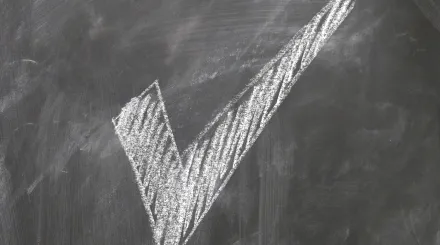 a large white chalk tick on a blackboard