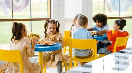 children eat a meal on yellow chairs