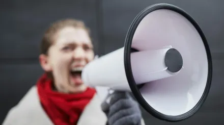 a woman in a red scarf shouts in a loudhailer or megaphone