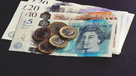 a pile of British Sterling coins on some differing currency notes