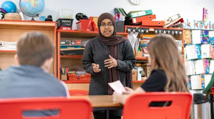 A woman in glasses and a headscarf teaches in a primary school