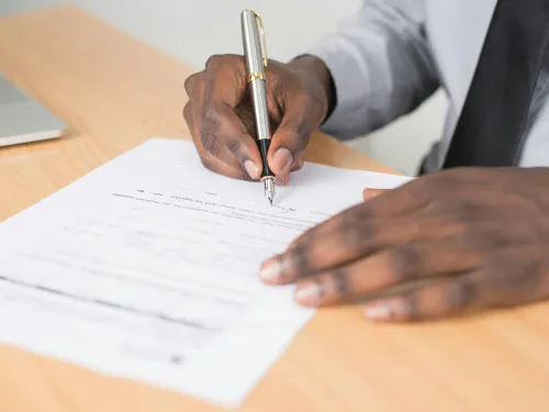 a man holds a pen to complete a form