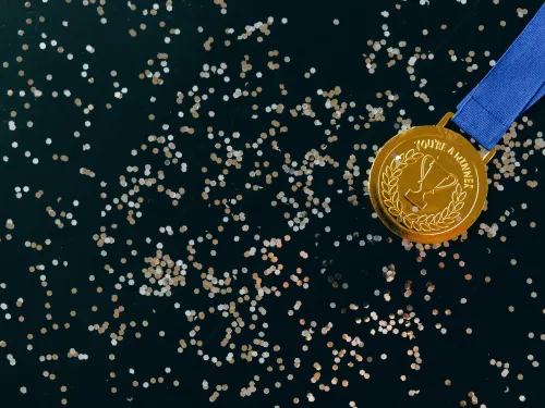 a gold medal on a dark background covered in glitter